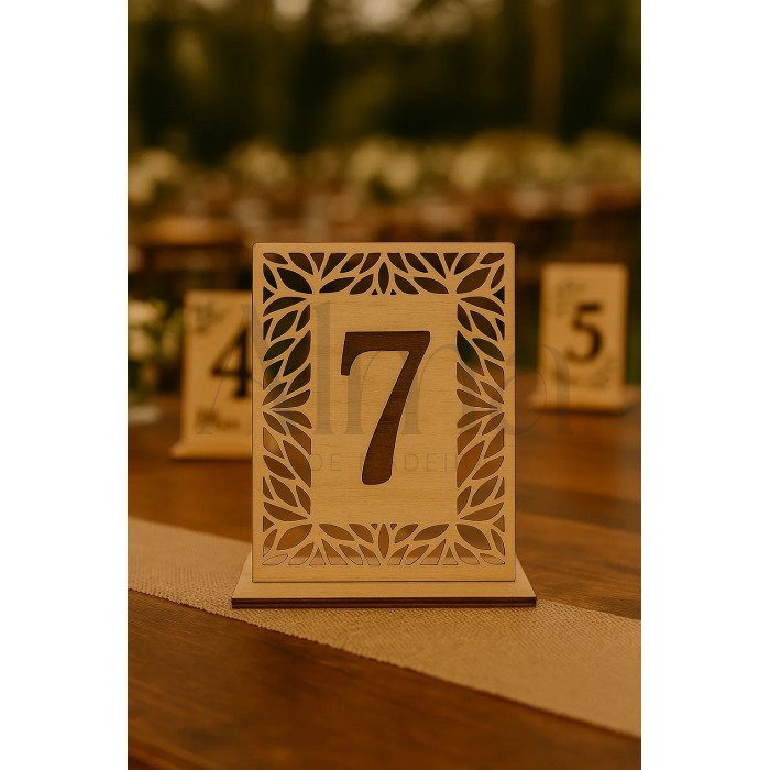 O modelo Número de Mesa Recortado destaca-se pelo seu formato quadrado em madeira clara e moldura recortada a laser, com padrão botânico.