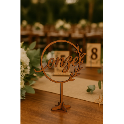 O modelo Número de Mesa Circular é feito em MDF e apresenta a palavra do número escrita em caligrafia fluída, envolta num aro circular com detalhe vegetal.