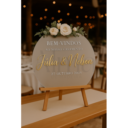 O modelo Placa Acrílico Fosco Redonda apresenta um design delicado, com formato circular, caligrafia dourada em relevo e um arranjo de flores no topo